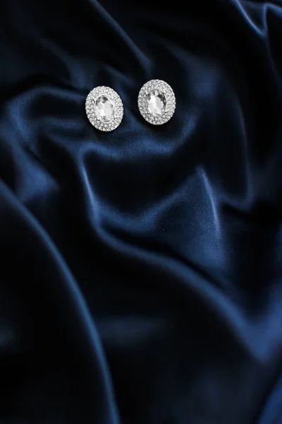 Lyxiga diamantörhängen på mörkblå sidenbakgrund, Holiday gl — Stockfoto