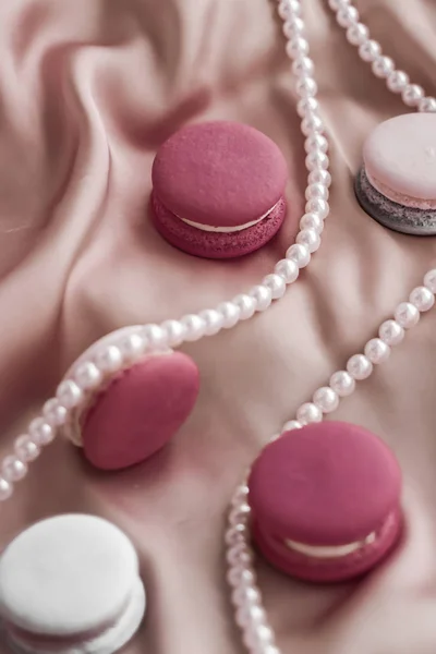 Sweet macaroons and pearls jewellery on silk background, parisia — ストック写真