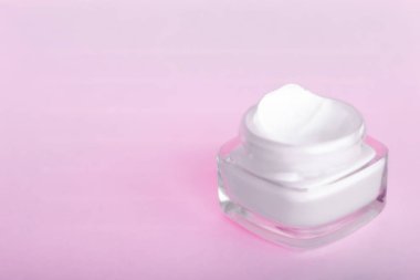 Pembe arka planda yüz kremi nemlendirici kavanozu, nemlendirici cilt