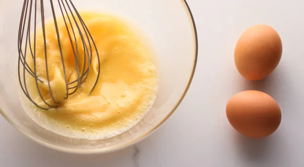 Membuat telur campur dalam mangkuk di atas meja marmer sebagai makanan buatan sendiri f — Stok Foto
