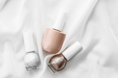 İpek arka planda oje şişeleri, Fransız manikür ürünleri.