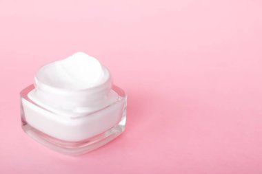 Pembe arka planda yüz kremi nemlendirici kavanozu, nemlendirici cilt