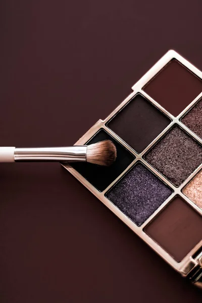 Eyeshadow palette and make-up brush on chocolate background, eye