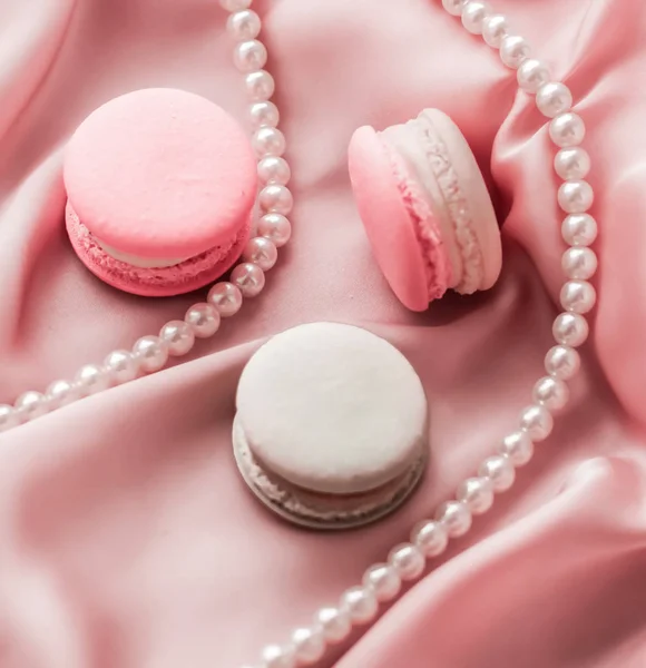 Sweet macaroons and pearls jewellery on silk background, parisia — ストック写真