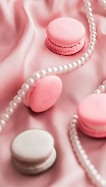 Sweet macaroons and pearls jewellery on silk background, parisia — ストック写真