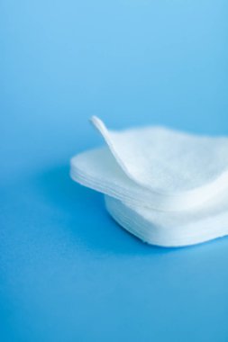 Mavi arka planda organik pamuk pedleri, kozmetik ürünleri ve makyaj malzemesi