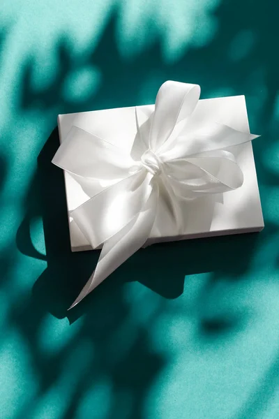 Luxury holiday white gift box with silk ribbon and bow on emeral