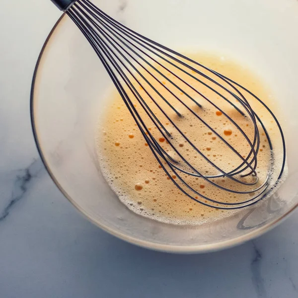 Membuat telur campur dalam mangkuk di atas meja marmer sebagai makanan buatan sendiri f — Stok Foto