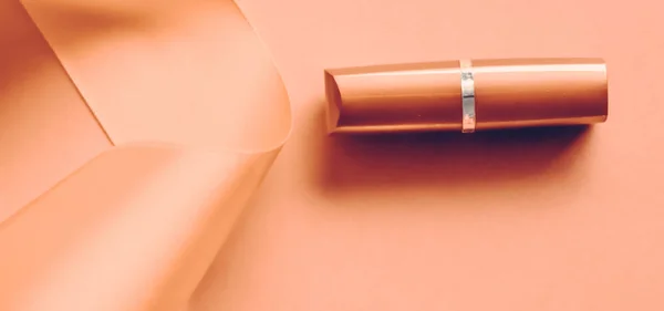 Lápiz labial de lujo y cinta de seda sobre fondo de vacaciones naranja, ma — Foto de Stock