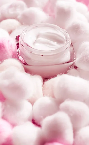 Luxury face cream for sensitive skin and pink cotton balls on ba