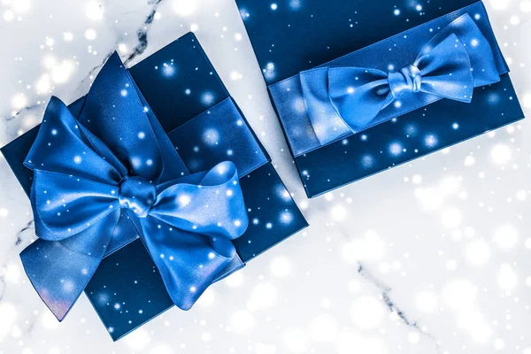 Зимова святкова подарункова коробка з блакитним шовковим бантом, сніговий блиск на болоті — стокове фото
