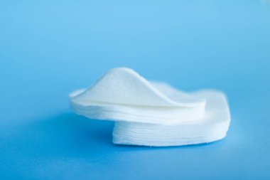 Mavi arka planda organik pamuk pedleri, kozmetik ürünleri ve makyaj malzemesi