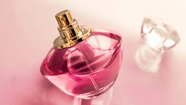 Pink perfume bottle on glossy background, sweet floral scent, gl