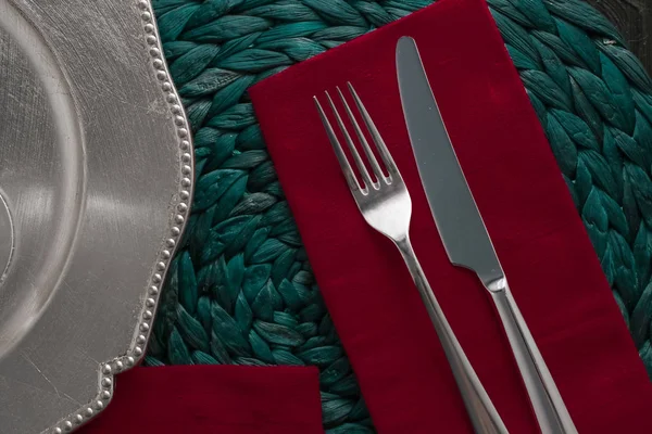 Holiday table setting with red napkin and silver cutlery, food s