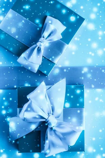 Zimní prázdninové dary a zářící sníh na zamrzlé modré pozadí, — Stock fotografie