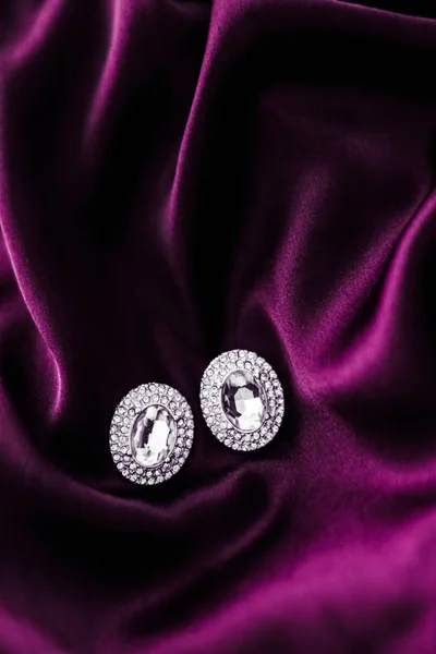 深粉色真丝织物上的豪华钻石耳环，节日玻璃 — 图库照片