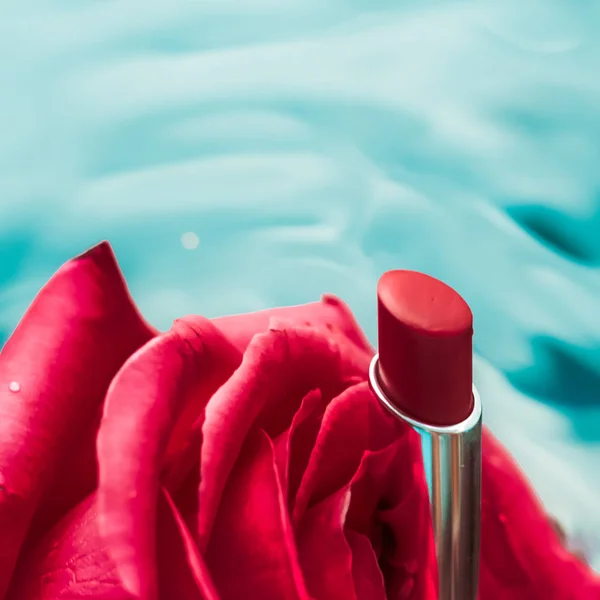Lápiz labial rojo y flor de rosa sobre fondo líquido, gl impermeable —  Fotos de Stock