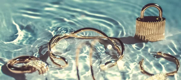 Gouden armbanden, oorbellen, ringen, sieraden op smaragd water bac — Stockfoto