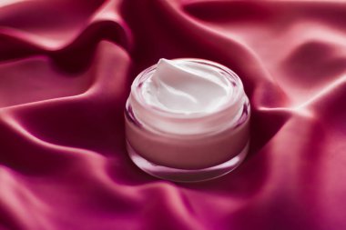 İpek arka planda yüz kremi nemlendirici kavanozu, nemlendirici cilt