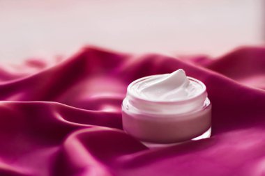 İpek arka planda yüz kremi nemlendirici kavanozu, nemlendirici cilt