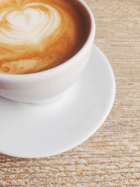 Kopje warme cappuccino in een cafetaria, koffie op een houten tafel i — Stockfoto