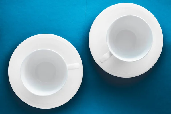 Ensemble de vaisselle en vaisselle blanche, tasse vide sur fond plat bleu — Photo