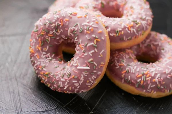 Frosted sprinkled donuts, sweet pastry dessert on rustic wooden