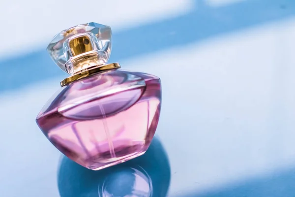 Pink perfume bottle on glossy background, sweet floral scent, gl