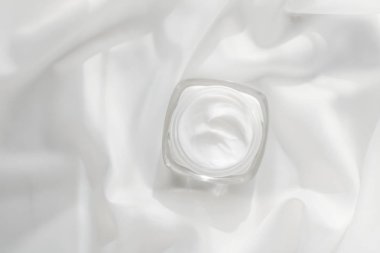 İpek arka planda yüz kremi nemlendirici kavanozu, nemlendirici cilt