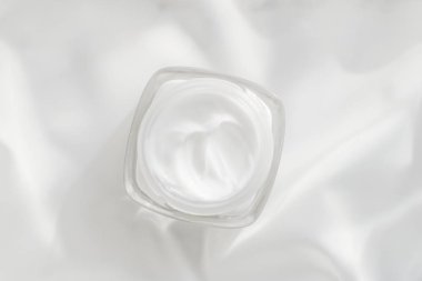 İpek arka planda yüz kremi nemlendirici kavanozu, nemlendirici cilt