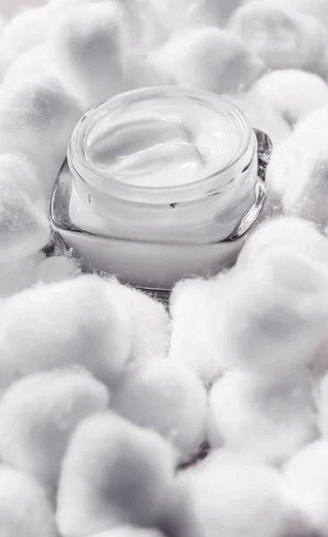 Luxury face cream for sensitive skin and white cotton balls on b