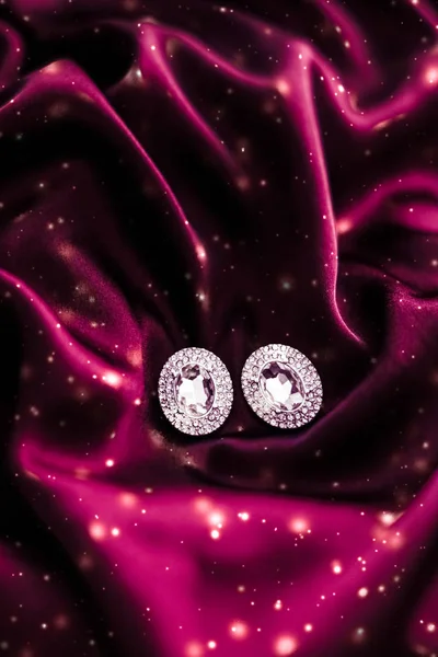 Lyxiga diamantörhängen på mörkt rött siden med snöglitter, Holi — Stockfoto