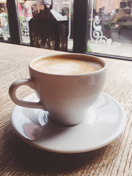 Xícara de cappuccino quente em uma cafetaria, café em uma mesa de madeira i — Fotografia de Stock