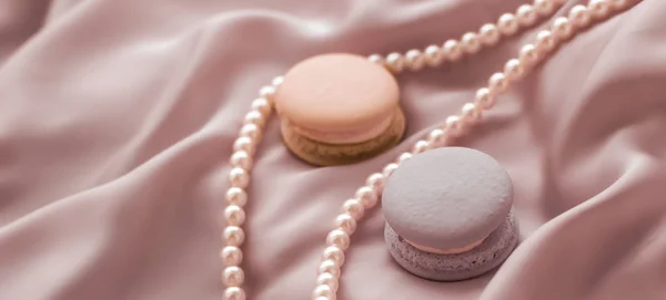 Macarrones dulces y joyas de perlas sobre fondo de seda, parisia — Foto de Stock