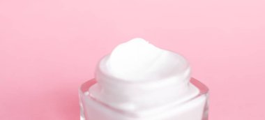 Pembe arka planda yüz kremi nemlendirici kavanozu, nemlendirici cilt