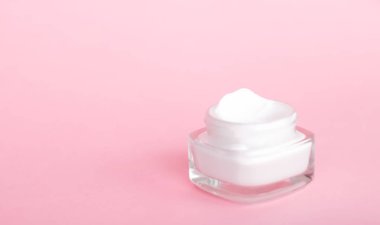 Pembe arka planda yüz kremi nemlendirici kavanozu, nemlendirici cilt