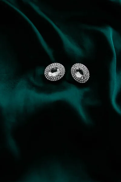 Розкішні діамантові сережки на темному смарагдовому зеленому шовку, святковий гламур — стокове фото
