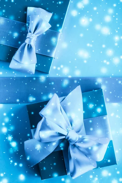 Winter vakantie geschenken en gloeiende sneeuw op bevroren blauwe achtergrond, — Stockfoto