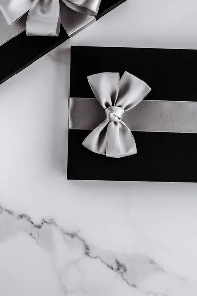 Luxury holiday gifts with silver silk ribbon and bow on marble b
