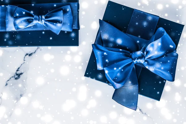 Winter holiday gift box with blue silk bow, snow glitter on marb — Stock Photo, Image