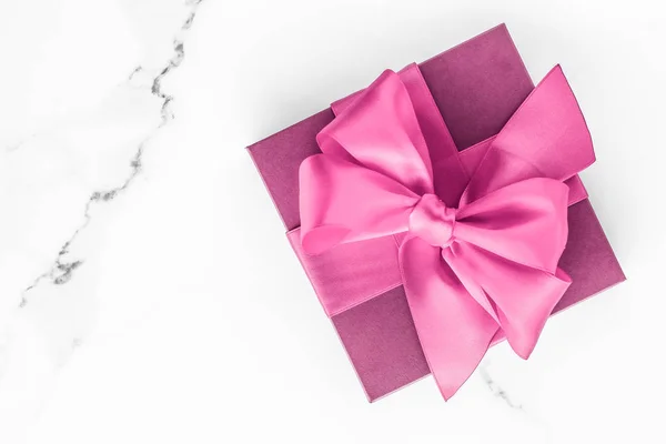 Розовый подарочная коробка с шелковым бантом на мраморном фоне, девочка шоу — стоковое фото