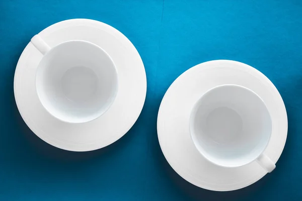 Ensemble de vaisselle en vaisselle blanche, tasse vide sur fond plat bleu — Photo