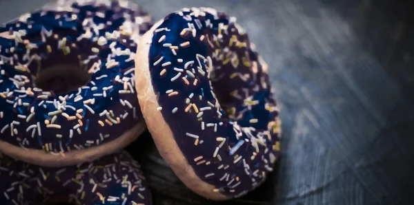 Frosted sprinkled donuts, sweet pastry dessert on rustic wooden — Stock Photo, Image