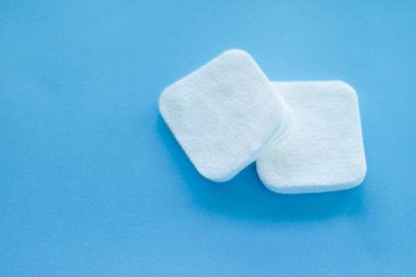 Mavi arka planda organik pamuk pedleri, kozmetik ürünleri ve makyaj malzemesi