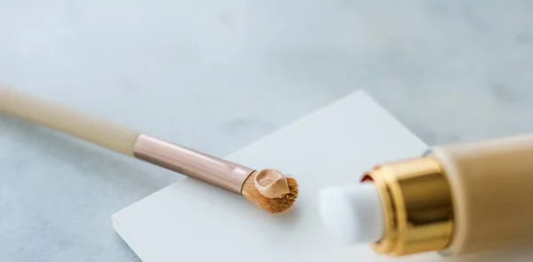 Makeup foundation bottle and contouring brush on marble, make-up