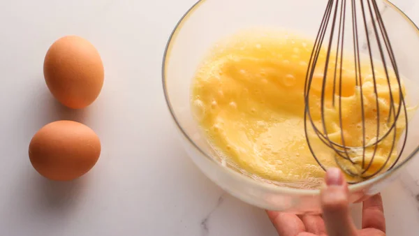 Ev yapımı yemek olarak mermer masada yumurta karıştırmak. — Stok fotoğraf