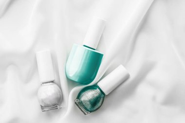 İpek arka planda oje şişeleri, Fransız manikür ürünleri.