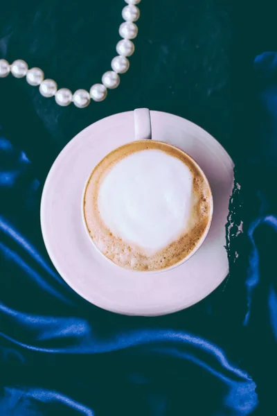 Cup of cappuccino for breakfast with satin and pearls jewellery