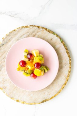 Yiyecek, içecek ve diyet konsepti - Pembe tabakta taze meyve vegan salatası, sağlıklı beslenme ve detoks