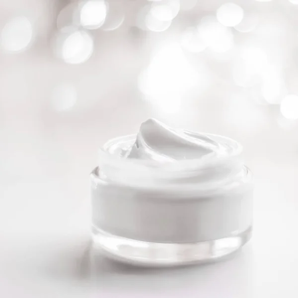 Facial cream moisturizer jar on holiday glitter background, anti-age skin care product close-up